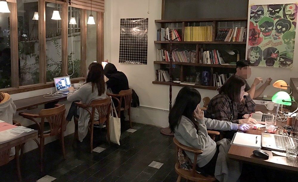 未央咖啡店 夜裡溫暖的座位區,旅人在書牆旁安靜工作